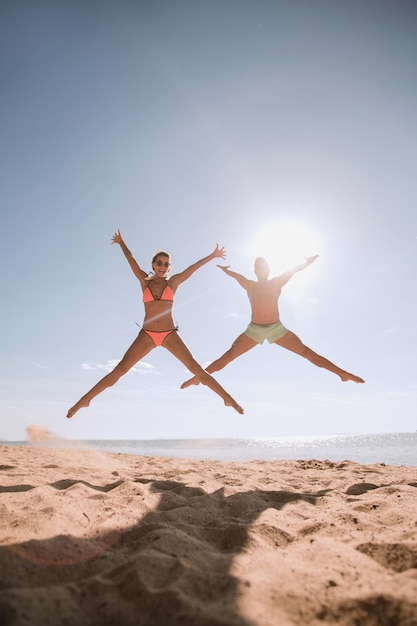 Immagine di coppia felice che salta sulla spiaggia.