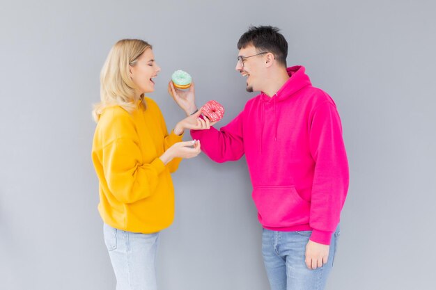 Immagine di coppia felice uomo e donna sorridente mentre mangiano ciambelle dolci insieme
