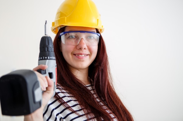 Immagine di donna in casco giallo con trapano in mano