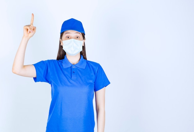 Immagine di donna in uniforme e maschera medica rivolta verso l'alto.