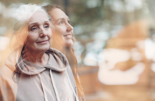 Immagine di doppia esposizione delle donne della nipote e della nonna. Ritratto di donna giovane e anziana. Amore, sogni e concetto di relazioni familiari felici.