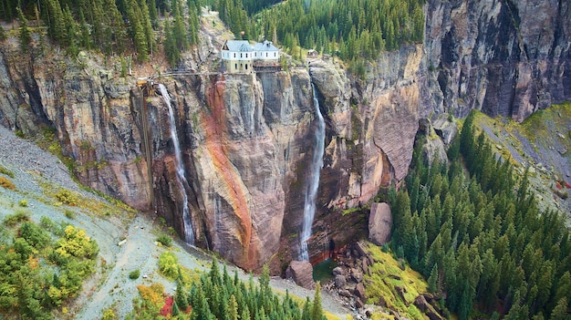 Immagine di due cascate sopra una gigantesca parete rocciosa con una centrale elettrica in cima