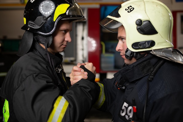 Immagine di due vigili del fuoco che indossano il casco e si stringono la mano
