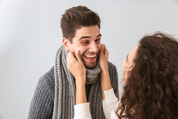 Immagine di felice coppia uomo e donna sorridente mentre si guardano l'un l'altro, isolato su muro grigio