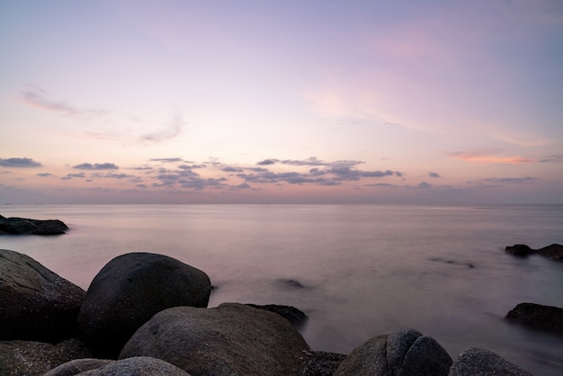 Immagine di lunga esposizione della vista sul mare drammatica del cielo con la roccia nella natura di paesaggio di tramonto della priorità alta.