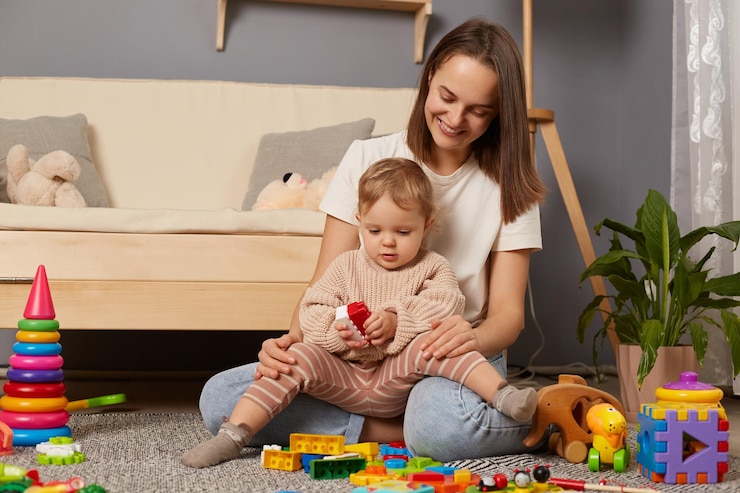 Foto immagine di madre e bambino sorridenti che giocano sul pavimento nella stanza dei bambini con la costruzione di una torre di blocchi colorati attività educative dei bambini con i genitori a casa