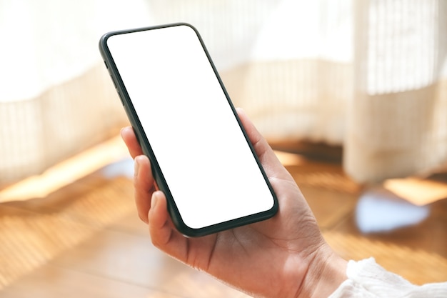 Immagine di mockup delle mani che tengono e utilizzando il telefono cellulare nero con lo schermo del desktop vuoto