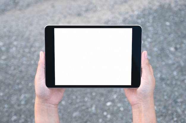 Immagine di mockup vista dall'alto delle mani che tengono tablet pc nero con schermo bianco vuoto