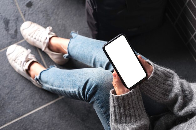 Immagine di mockup vista dall'alto di una donna che tiene il telefono cellulare nero con lo schermo del desktop vuoto