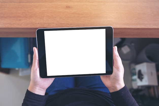 Immagine di mockup vista dall'alto di una donna che tiene un tablet pc nero con schermo bianco vuoto