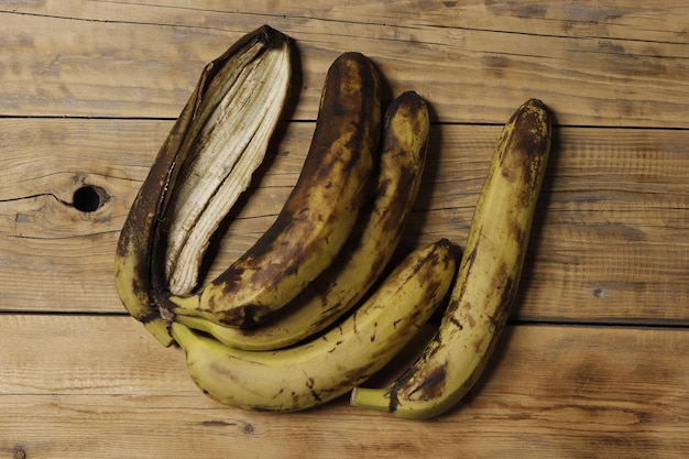 Immagine di quattro banane marroni su uno sfondo di legno