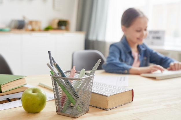 Immagine di sfondo della ragazza che utilizza il computer portatile mentre studiava a casa, concentrarsi sul supporto della matita e sui libri, copia dello spazio