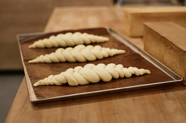 Immagine di sfondo di panini crudi con nodo sul vassoio in panetteria pronti per la cottura dello spazio per la copia