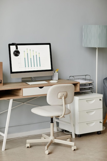 Immagine di sfondo verticale del posto di lavoro minimo dell'ufficio domestico in bianco con il computer sulla scrivania in legno poliziotto