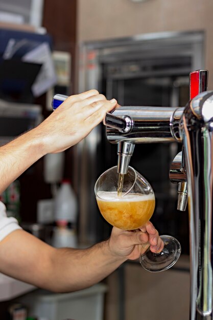 Immagine di un barista che versa birra alla spina in un bicchiere in un pub o in un ristorante