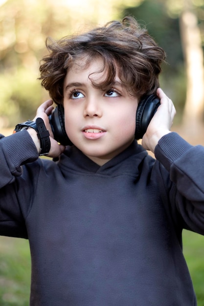 Immagine di un bel ragazzo con lunghi capelli biondi in giardino ad ascoltare musica e alzare lo sguardo