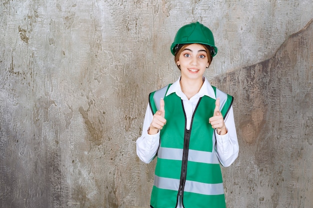 Immagine di un bellissimo architetto donna con un casco verde che punta a qualcosa