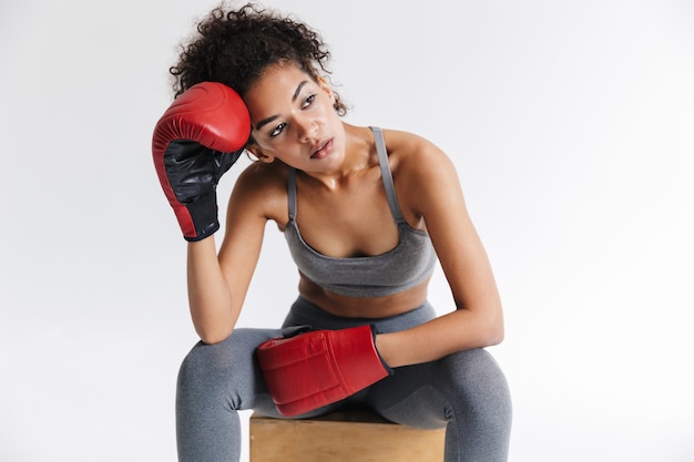 Immagine di un bellissimo giovane pugile sportivo fitness donna africana in posa isolato sul muro bianco in guanti.