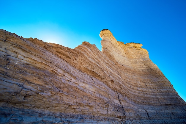 Immagine di un grande muro di roccia bianca contro il cielo blu e il sole che blocca