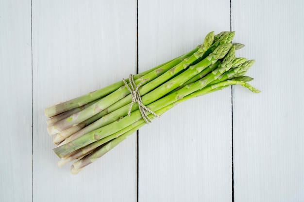 Immagine di un mazzo di asparagi crudi verdi freschi sullo sfondo del tavolo in legno Girato in studio