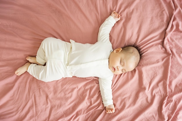 Immagine di un neonato sdraiato su un letto rosa