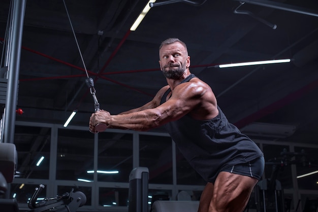 Immagine di un potente atleta che si esercita in un crossover in palestra. Tricipiti di pompaggio. Concetto di fitness e bodybuilding. Tecnica mista