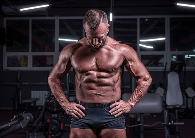 Immagine di un potente atleta in posa in palestra. Concetto di fitness e bodybuilding. Tecnica mista