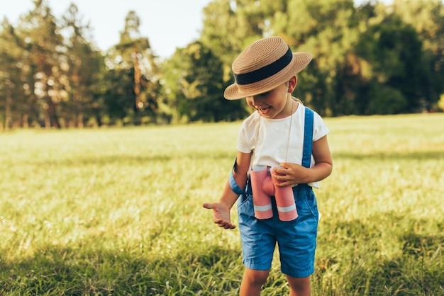 Immagine di un ragazzino carino che gioca con un binocolo alla ricerca di un'immaginazione o di un'esplorazione in una giornata estiva nel parco Bambino felice che gioca all'aperto nella foresta Concetto di infanzia