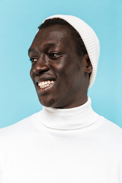Immagine di un ragazzo afroamericano felice in abiti bianchi che sorride e guarda da parte
