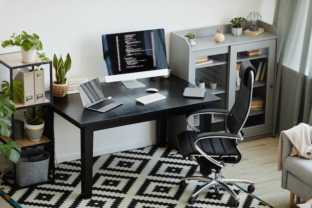 Immagine di un ufficio moderno con tavolo con monitor di computer e laptop sul posto di lavoro per programmatore di computer