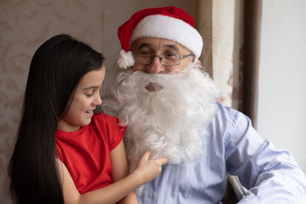 Immagine di un uomo anziano che indossa un cappello da Babbo Natale mentre gioca con i suoi nipoti