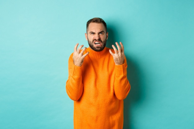 Immagine di un uomo arrabbiato che sembra deluso e pazzo, stringe la mano e fa smorfie con disprezzo, in piedi