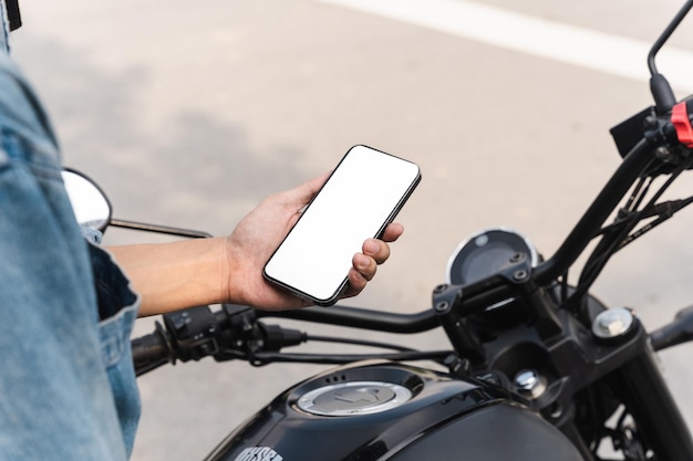 Immagine di un uomo asiatico seduto in moto utilizzando il telefono cellulare