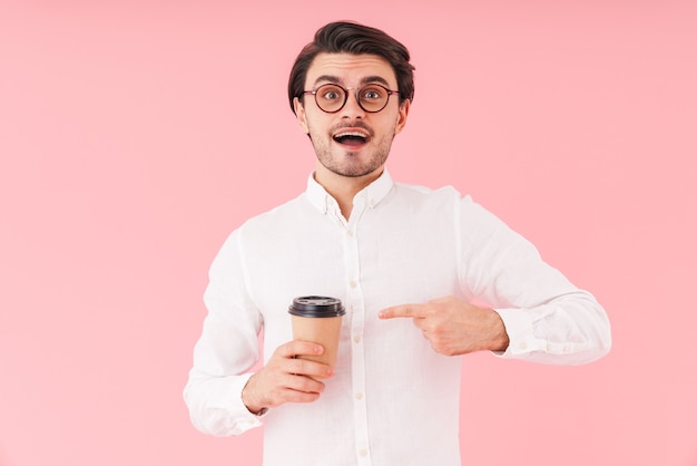 Immagine di un uomo caucasico stupito che indossa occhiali tenendo e puntando il dito al bicchiere di carta isolato