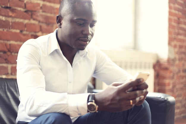 Immagine di un uomo d'affari afroamericano in abito formale sul suo cellulare