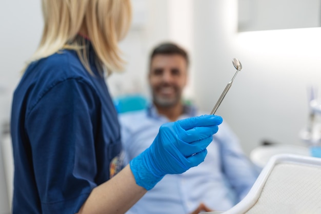 Immagine di un uomo soddisfatto seduto sulla poltrona del dentista al centro medico mentre un medico professionista si aggiusta i denti
