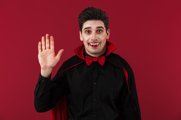 Immagine di un vampiro felice con sangue e zanne in costume di halloween nero che gesturing