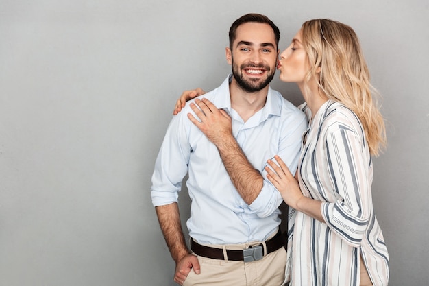 Immagine di una bella coppia in abiti casual che sorride mentre la donna bacia un bell'uomo isolato