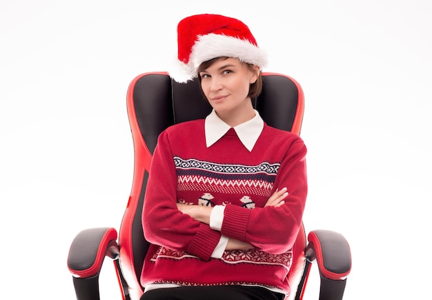 Immagine di una bella donna con un maglione natalizio in posa su una sedia da ufficio su uno sfondo bianco. Concetto di vacanza. Eventi aziendali. Tecnica mista