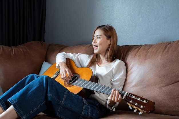 Immagine di una bella donna felice che suona la chitarra e compone una canzone