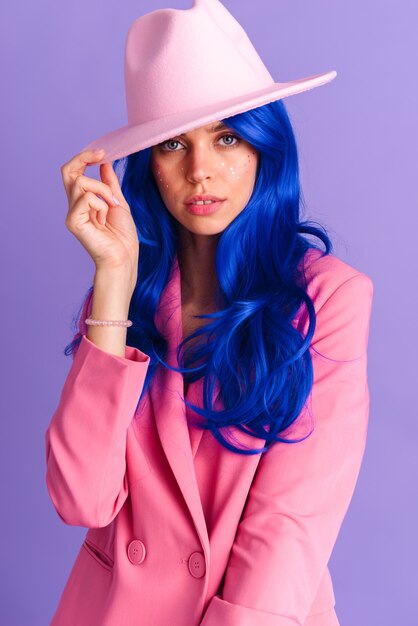 Immagine di una bella donna seducente con una parrucca blu navy in bilico e che sembra isolata su un muro viola