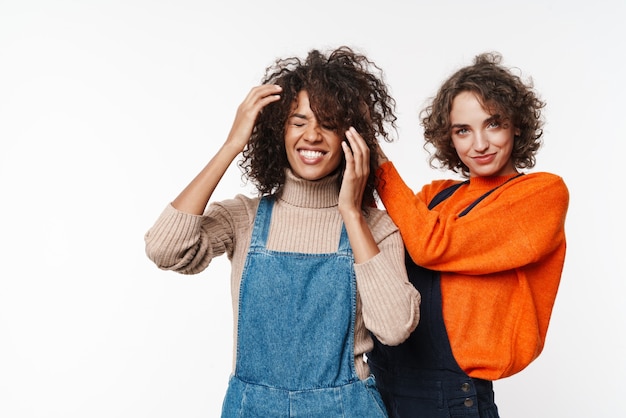 Immagine di una bella felice allegra ottimista due amiche multirazziali in tute di jeans