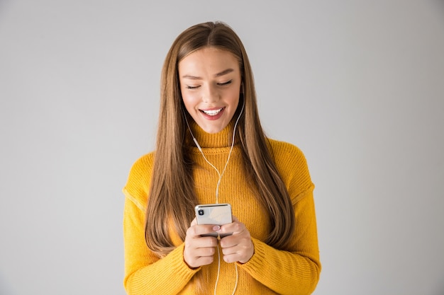 Immagine di una bella giovane donna felice isolata sopra il muro grigio utilizzando il telefono cellulare.