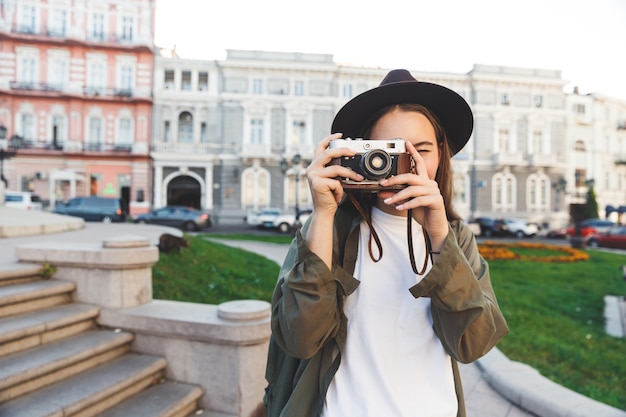 Immagine di una bella giovane donna fotografa turista che cammina all'aperto in una bella giornata di primavera che tiene la macchina fotografica