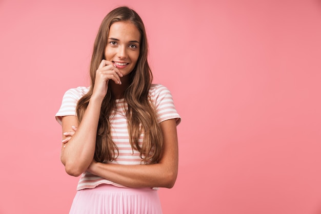 Immagine di una bella ragazza contenta che indossa abiti a righe che sorride e sembra isolata sul muro rosa