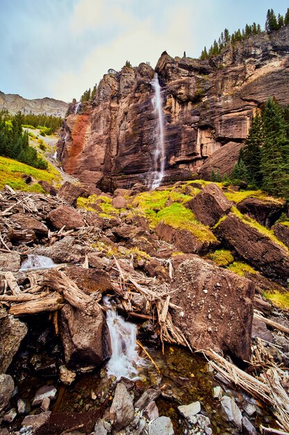 Immagine di una cascata gigantesca su scogliere verticali che portano a massi di muschio nella valle