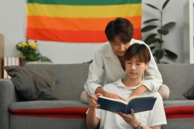 Immagine di una coppia gay appassionata seduta in salotto e che legge un libro Concetto di amore e stile di vita LGBT