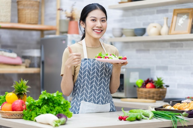 Immagine di una donna asiatica che prepara l'insalata in cucina