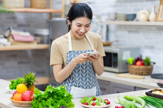 Immagine di una donna asiatica che prepara l'insalata in cucina