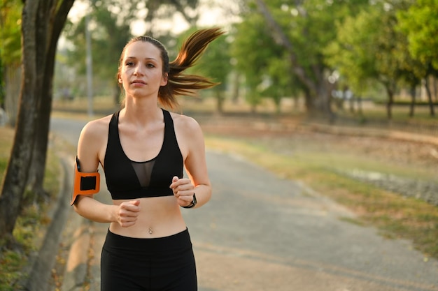 Immagine di una donna fitness attraente che fa jogging nel parco con la luce dell'alba Fitness sport e concetto di stile di vita sano